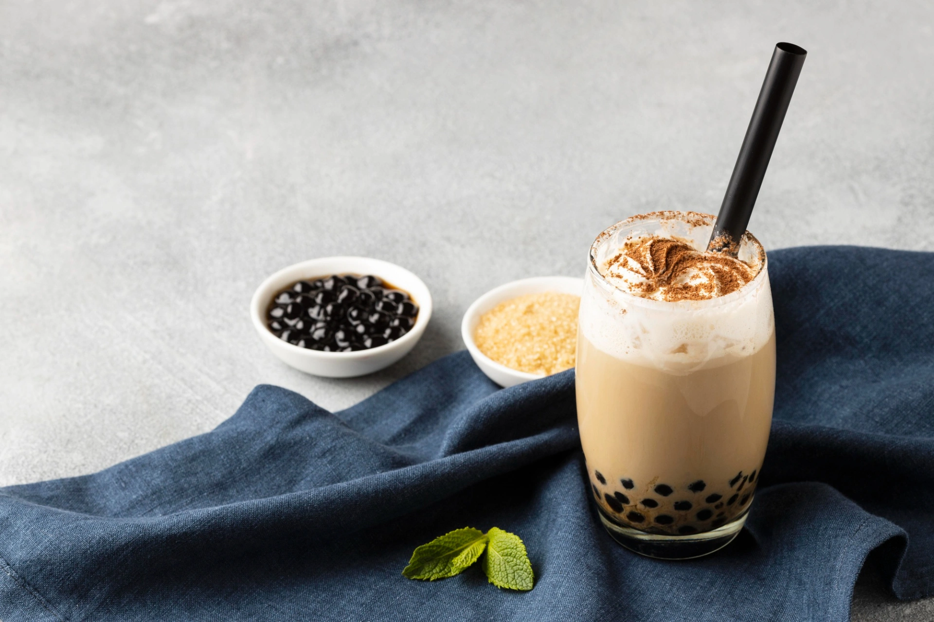 Bubble milk tea topped with Welong instant boba pearls next to a bowl of ready-to-eat tapioca pearls